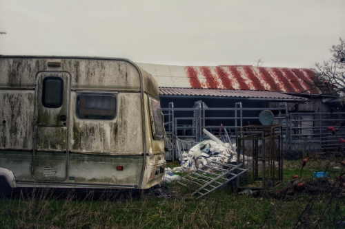Decaying caravan and rusty farm sheds